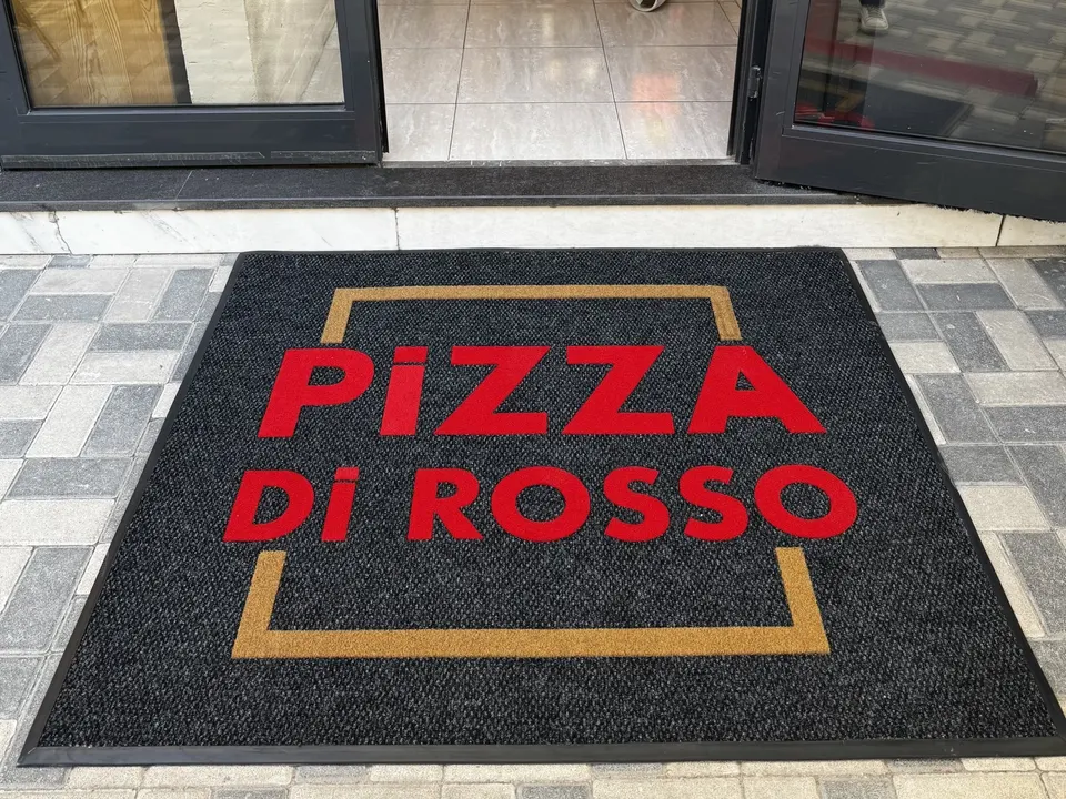 Restoran kapısı önünde kırmızı yazılı logolu paspas